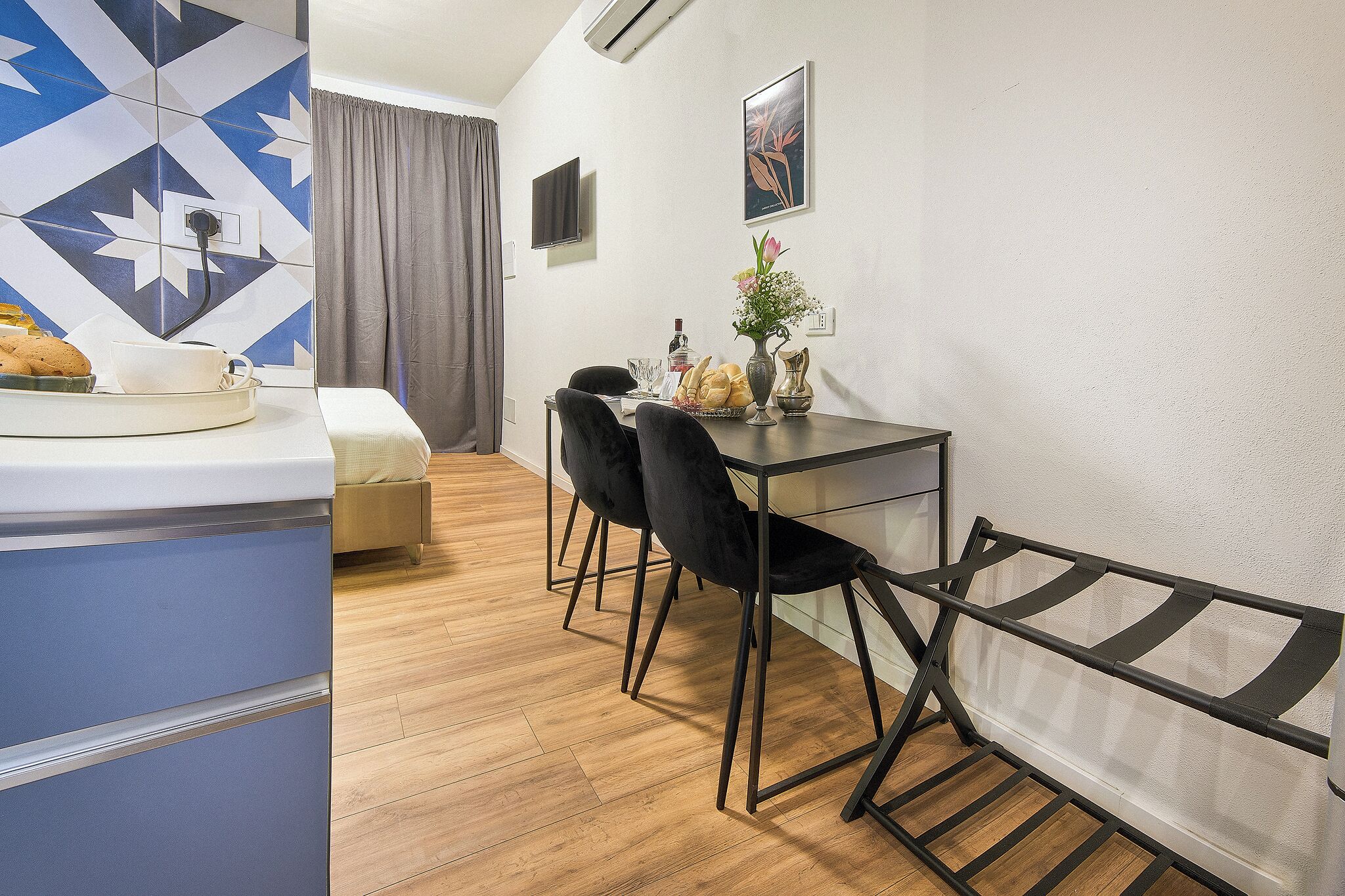Una habitación pequeña con zona de comedor, una cama y una pequeña mesa con sillas.