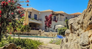 A hotel with a pool, outdoor seating, and a rocky landscape. - Cassiopeia 2-Beds Lower Apt on Beach with Pool (Maleme)