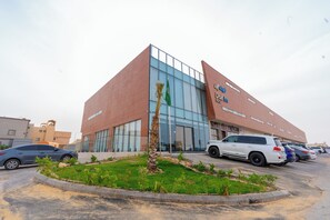 A modern building with a glass facade and a palm tree in the center.