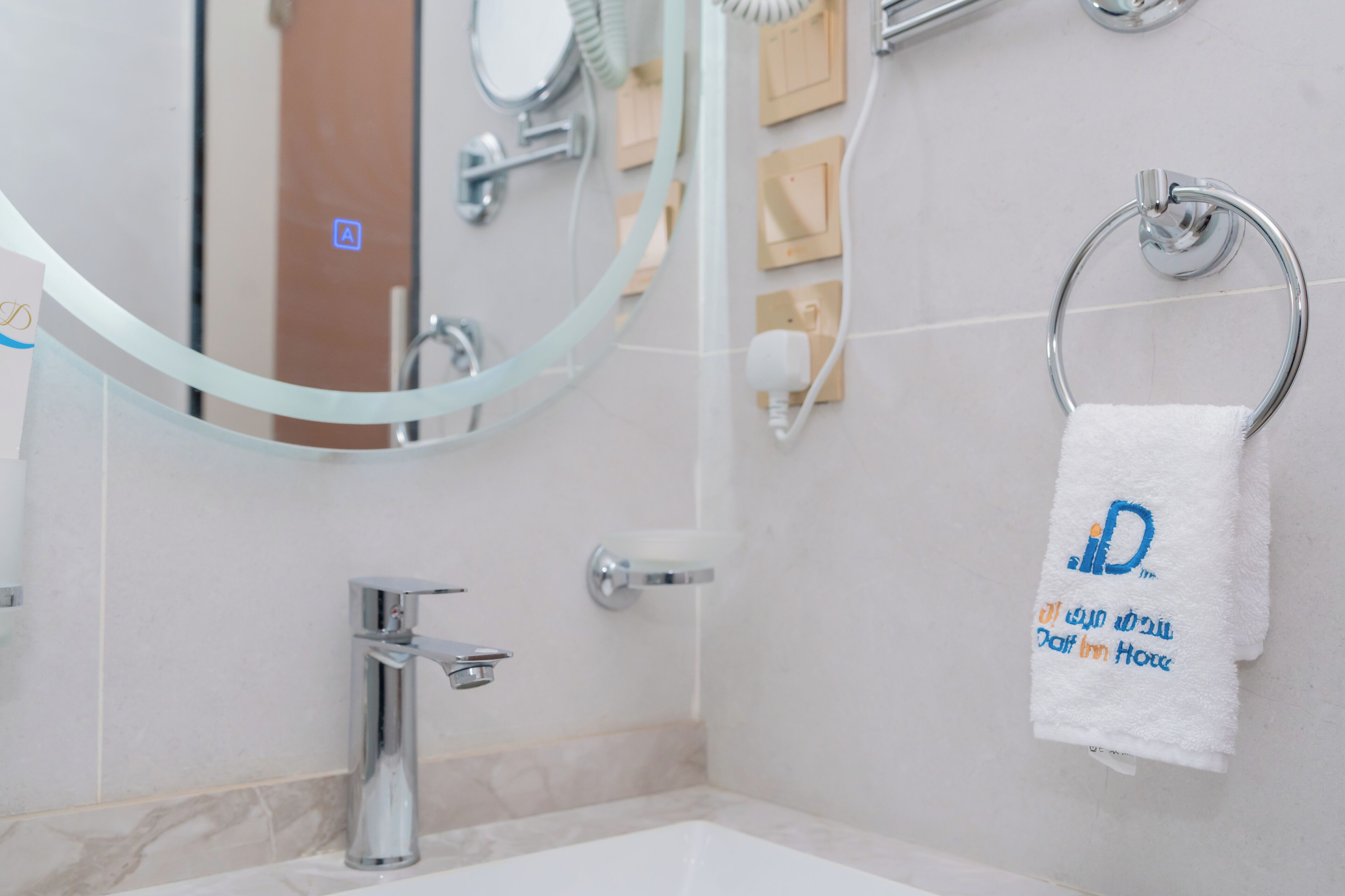 A bathroom with a white sink, chrome faucet, and a towel rack with a white towel hanging on it.
