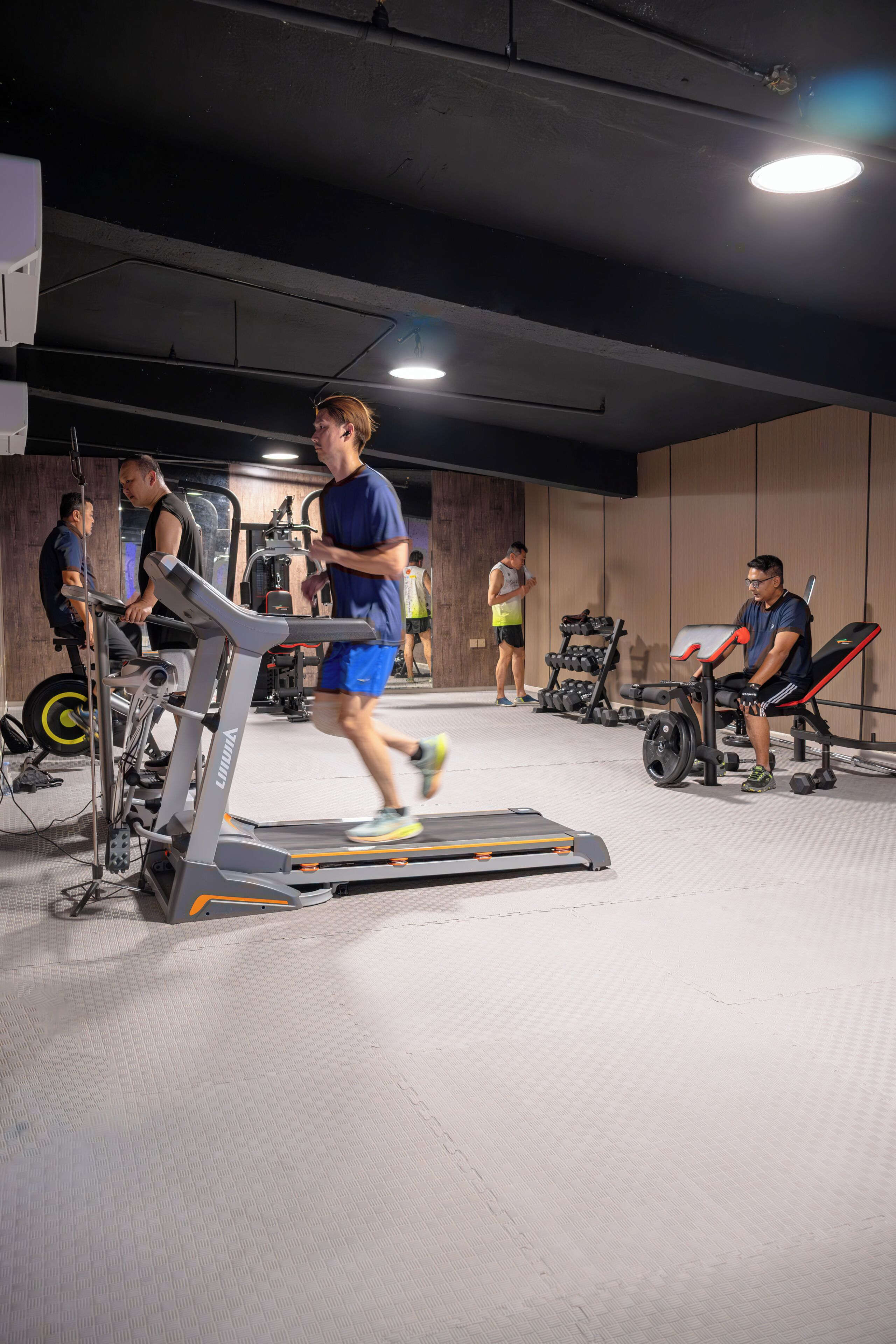 A gym with treadmills, weight machines, and a person running.