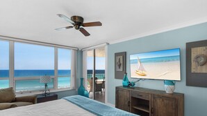 A bedroom with a large bed, a ceiling fan, a TV, and a view of the beach. - Great Beach Views from 6th Floor at Hidden Dunes! (Miramar Beach)