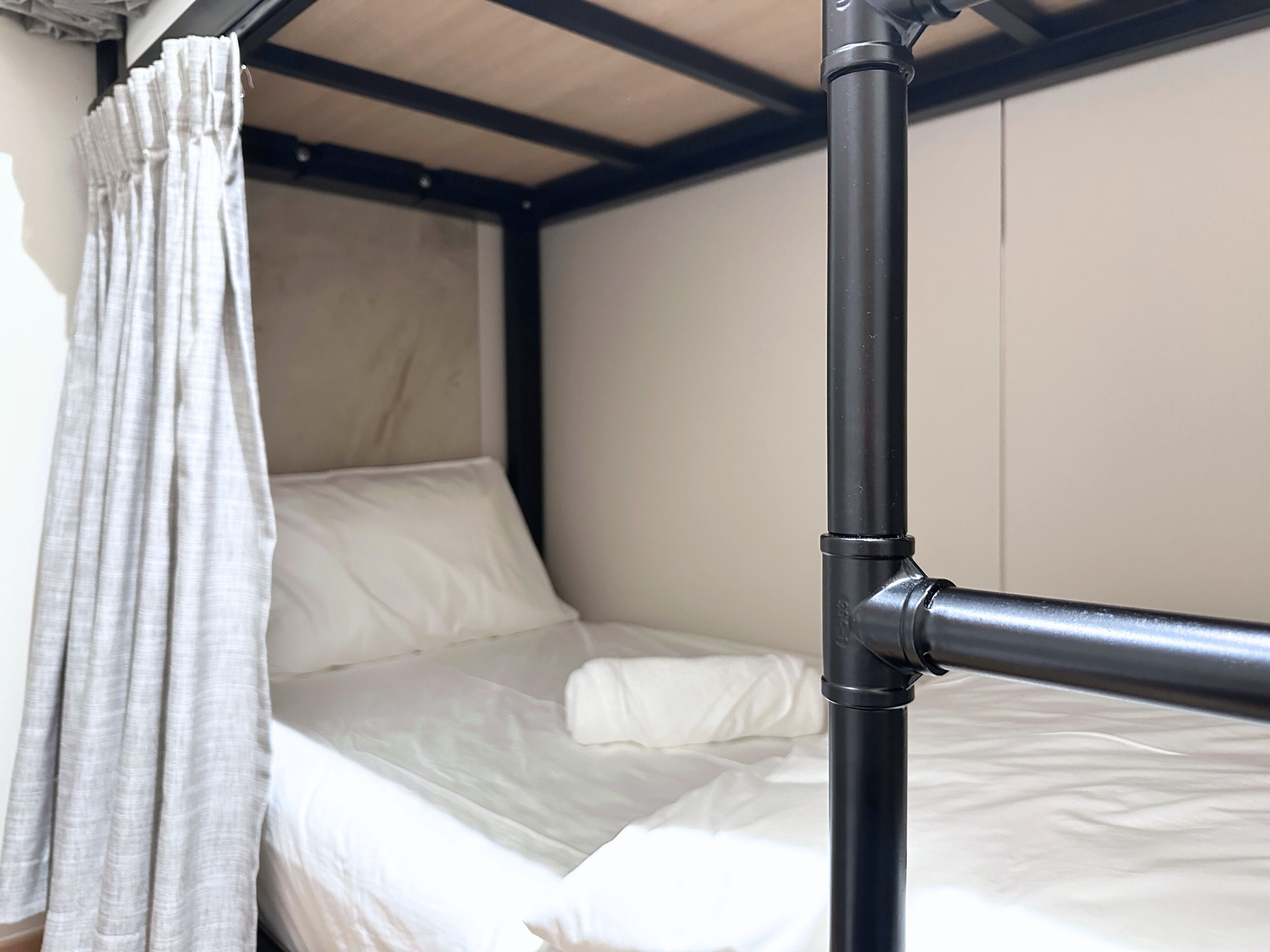 Una cama litera con cabecera, cortina y estructura de metal.