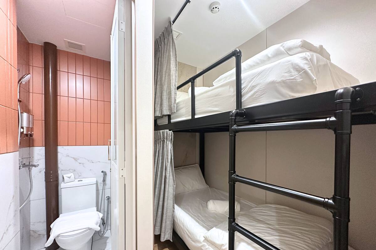 A bunk bed room with a shower, toilet, and a curtain.