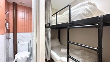 A bunk bed room with a shower, toilet, and a curtain.