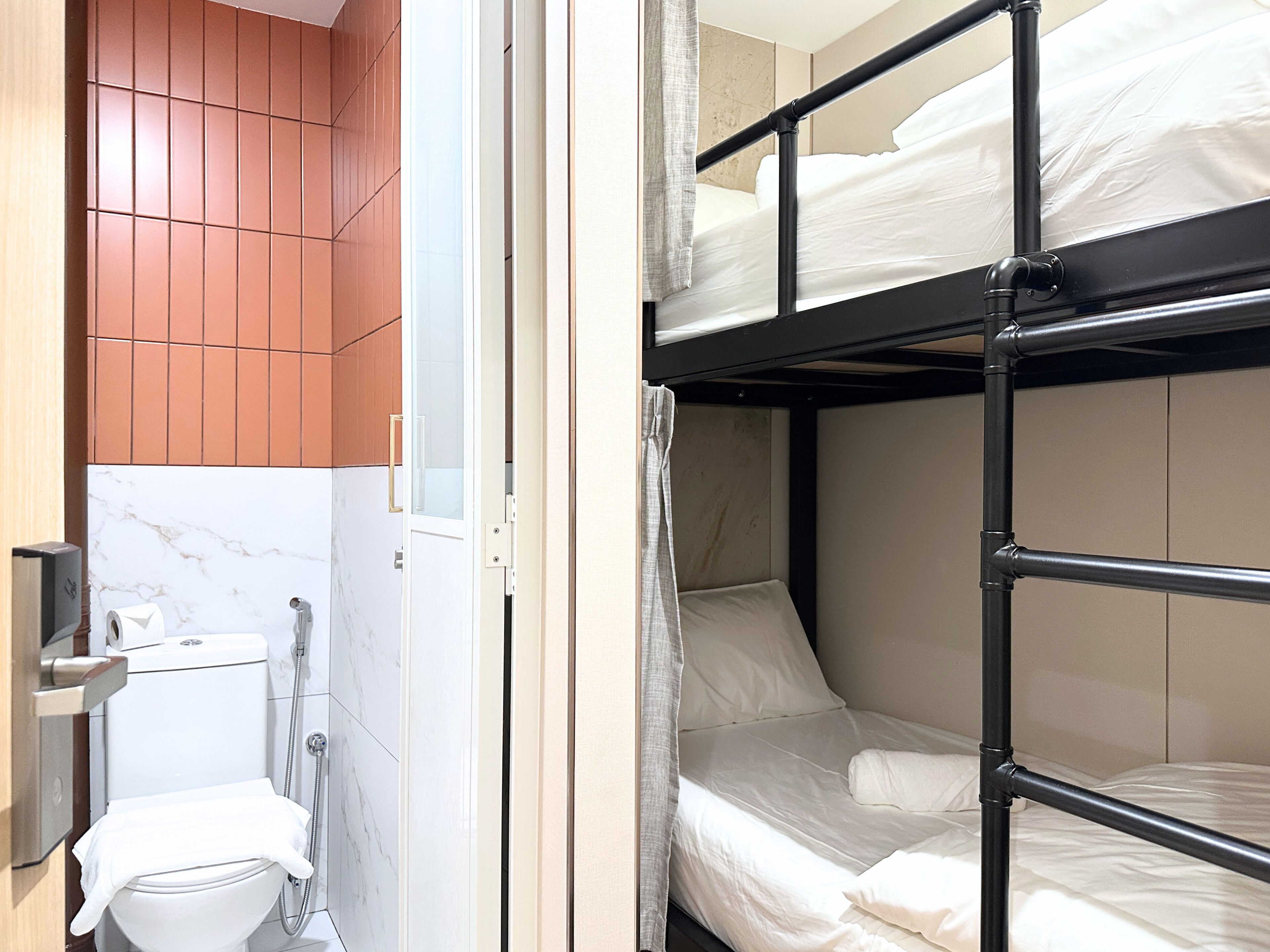 A compact hotel room with a bunk bed, a toilet, and a shower.