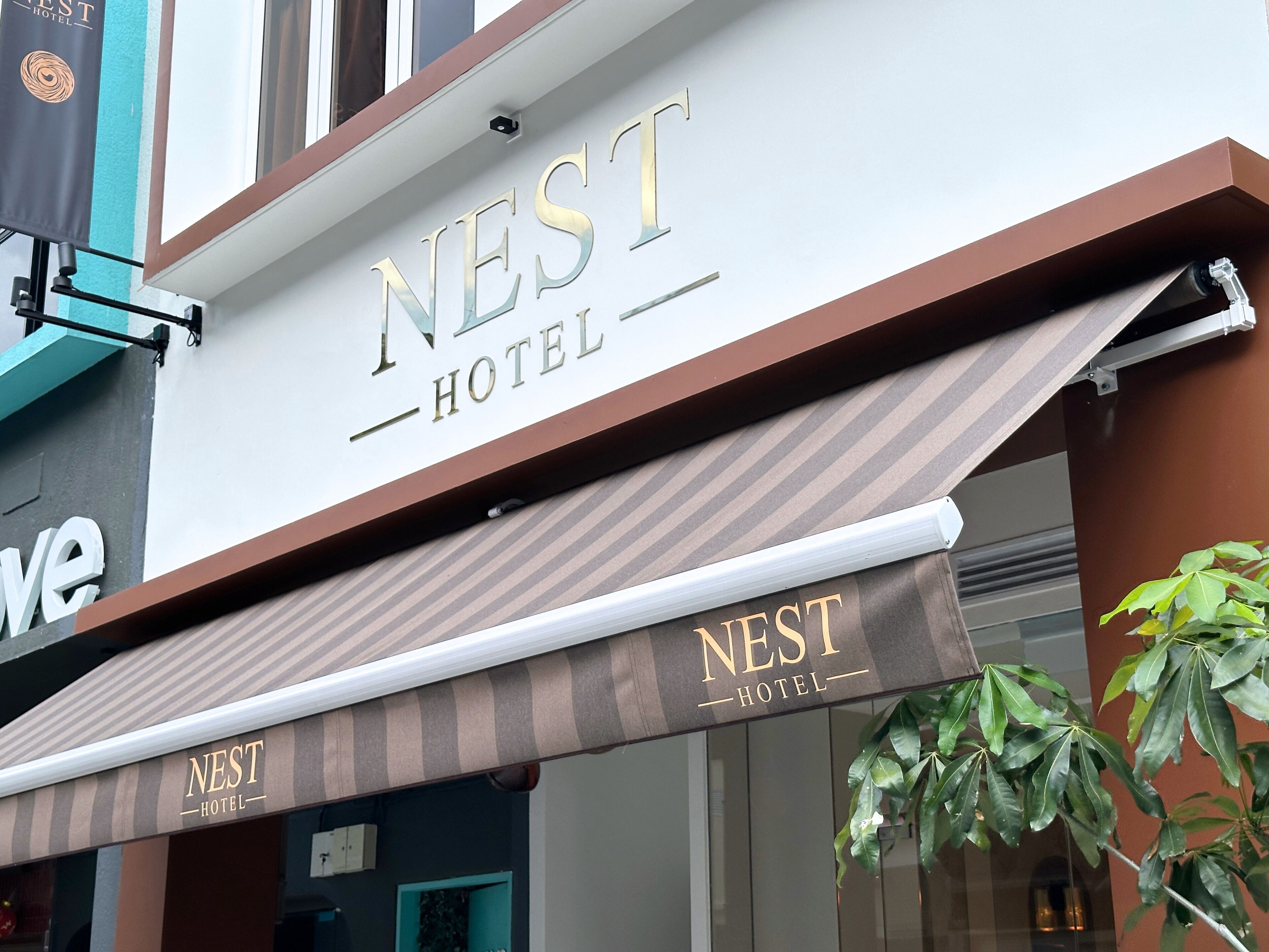 La façade de l’hôtel Nest, avec son auvent rayé et son panneau indicateur.