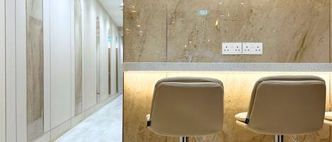 A corridor with a marble wall and two bar stools with metal legs.