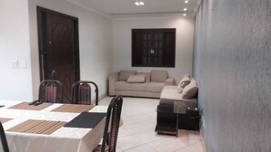 A living room with a sofa, a dining table with chairs, and a TV stand. - House near Pampulha (Contagem)