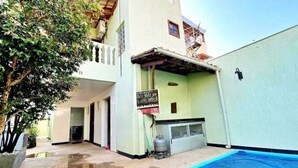 A two-story building with a swimming pool, a covered patio, and a visible water tank. - House near Pampulha (Contagem)