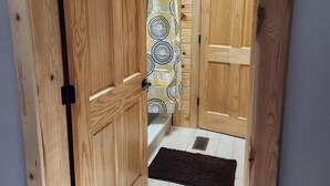 A wooden room with a skylight, a shower curtain, and a dark rug.