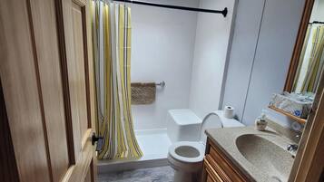 Un baño con tragaluz, ducha, inodoro y armarios de madera.