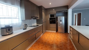 Una cocina moderna con electrodomésticos de acero inoxidable, un ventanal grande y piso de baldosas.