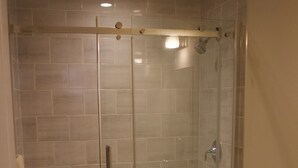 A glass-enclosed shower stall with a white toilet and a beige sink.