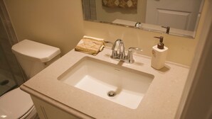 A bathroom with a white sink, a mirror above it, and a toilet to the left.