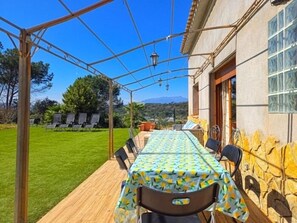 Un espace extérieur aménagé pour les repas, avec une table et des chaises, une pergola et un mur en pierre.