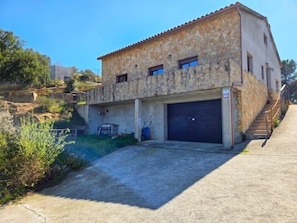 Un bâtiment en pierre de deux étages, doté d’un garage, d’un escalier et surplombant un ciel dégagé.