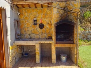 An outdoor stone-built structure with a built-in oven, a sink, and a hanging lantern.