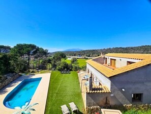 A house with a swimming pool, a well-maintained lawn, and a view of the countryside.
