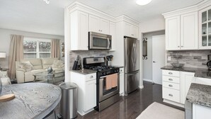 A modern kitchen with white cabinetry, stainless steel appliances, and a granite countertop. - 4.2 mi - TBK Sports Complex, 8.6 mi - Airport (Bettendorf)