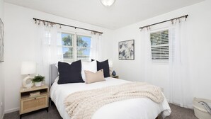 A bedroom with a bed, bedside tables, a lamp, and a window with curtains. - 4.2 mi - TBK Sports Complex, 8.6 mi - Airport (Bettendorf)