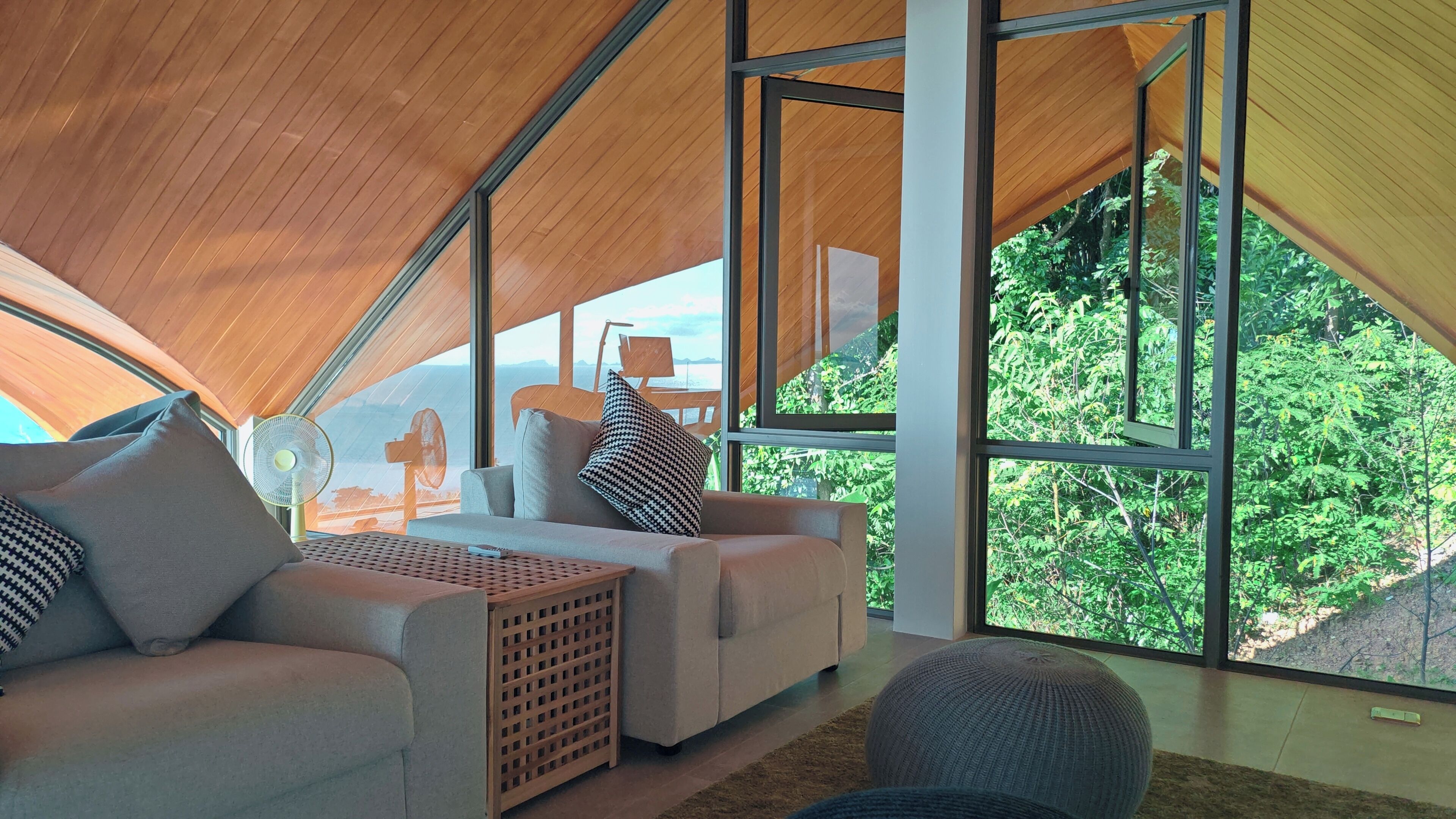 A modern, spacious living area with large windows offering a view of lush greenery.