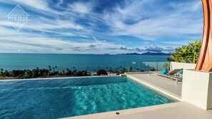 Une piscine offrant une vue dégagée sur l’océan et les montagnes au loin.