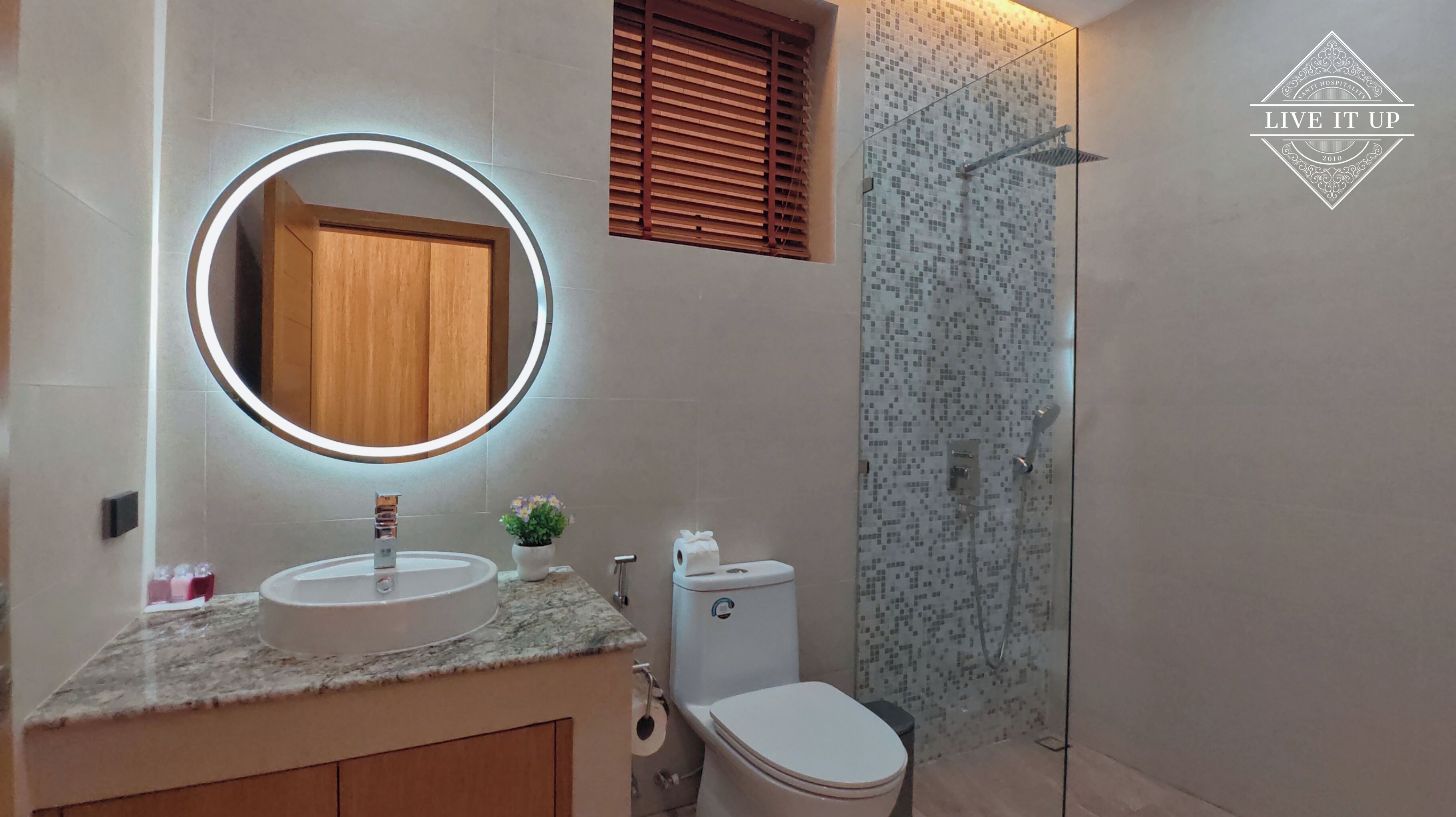 A bathroom with a round mirror, a sink, a toilet, and a shower.