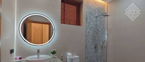 A bathroom with a round mirror, a sink, a toilet, and a shower.