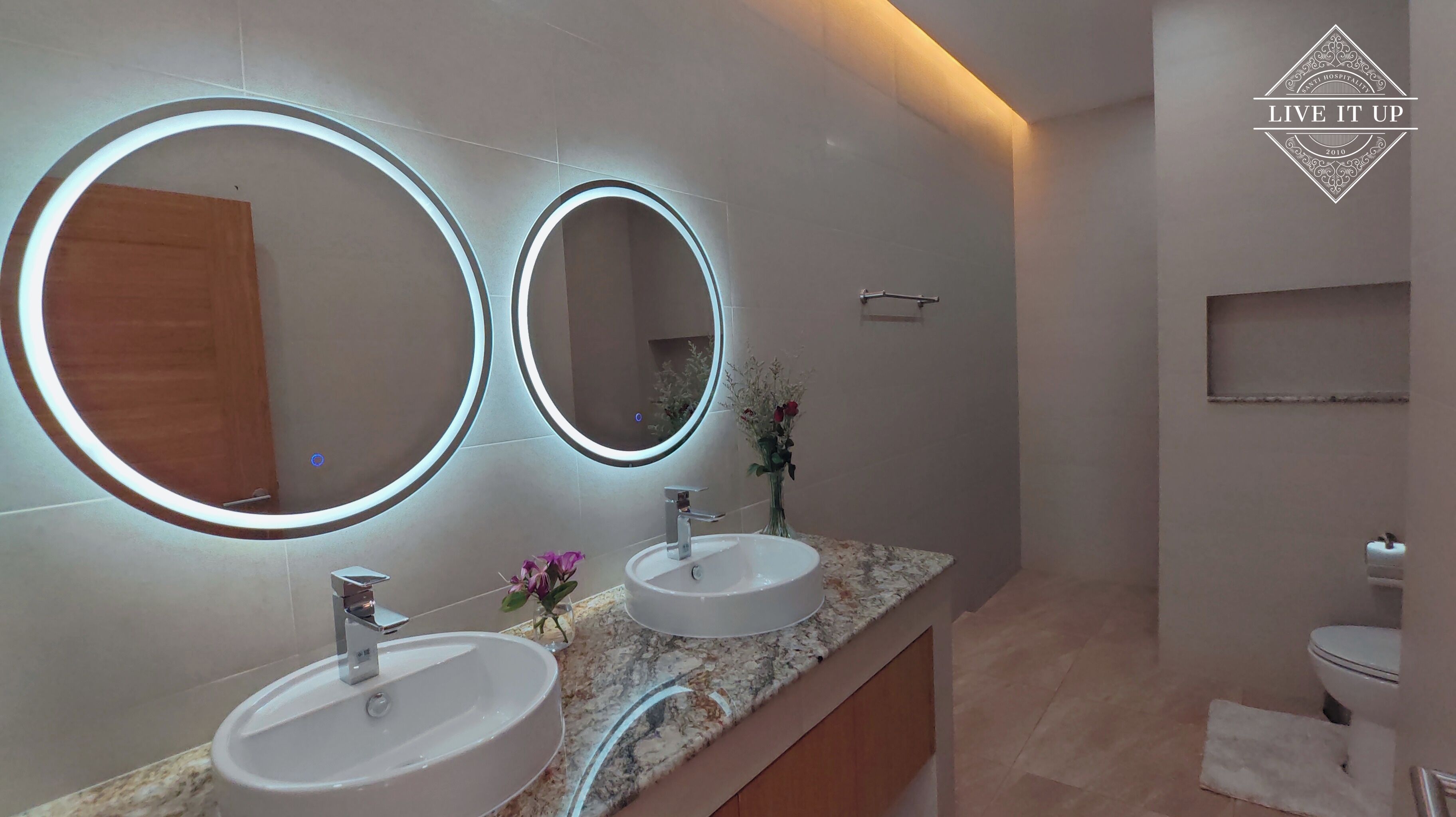 A modern bathroom with two sinks, large mirrors, and a wooden vanity.