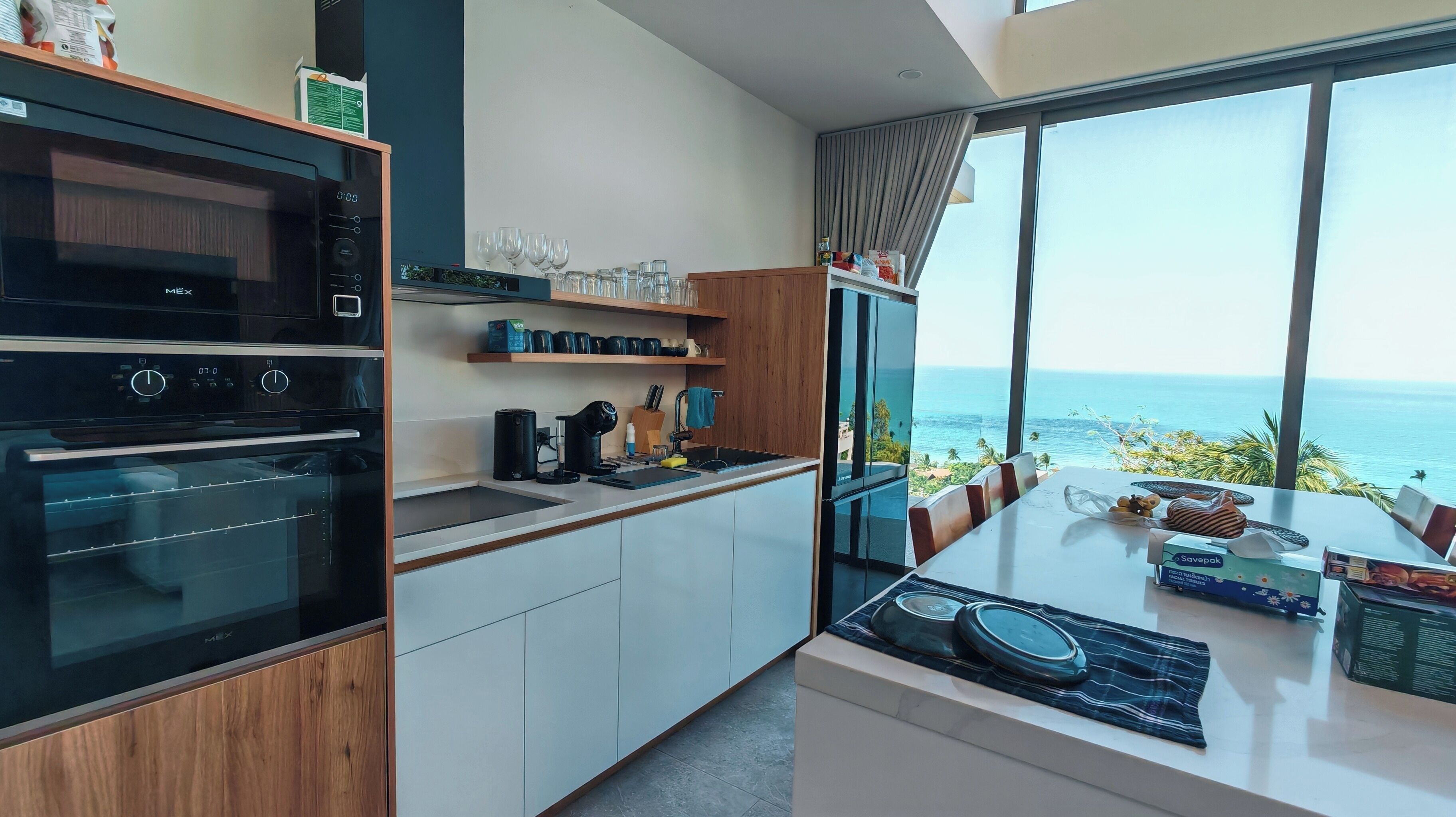Una cocina moderna con una isla grande, electrodomésticos integrados y vista al océano.