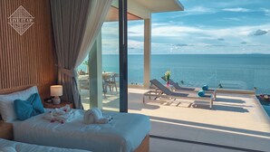 A hotel room with a bed, a nightstand, a lamp, and a view of the ocean. - Santi Pura Villas (Koh Samui)
