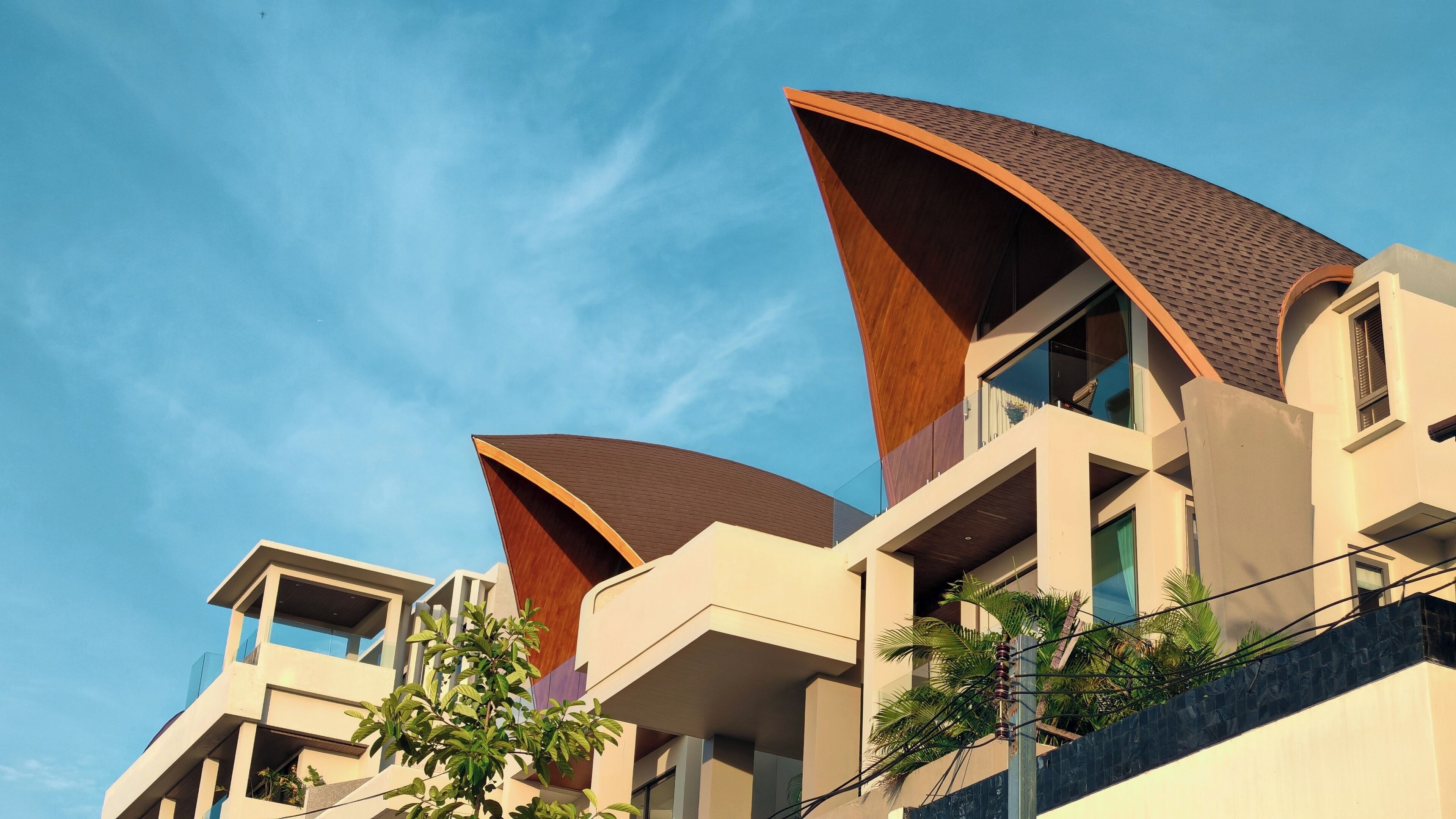 A modern building with a unique curved roof design and multiple balconies.