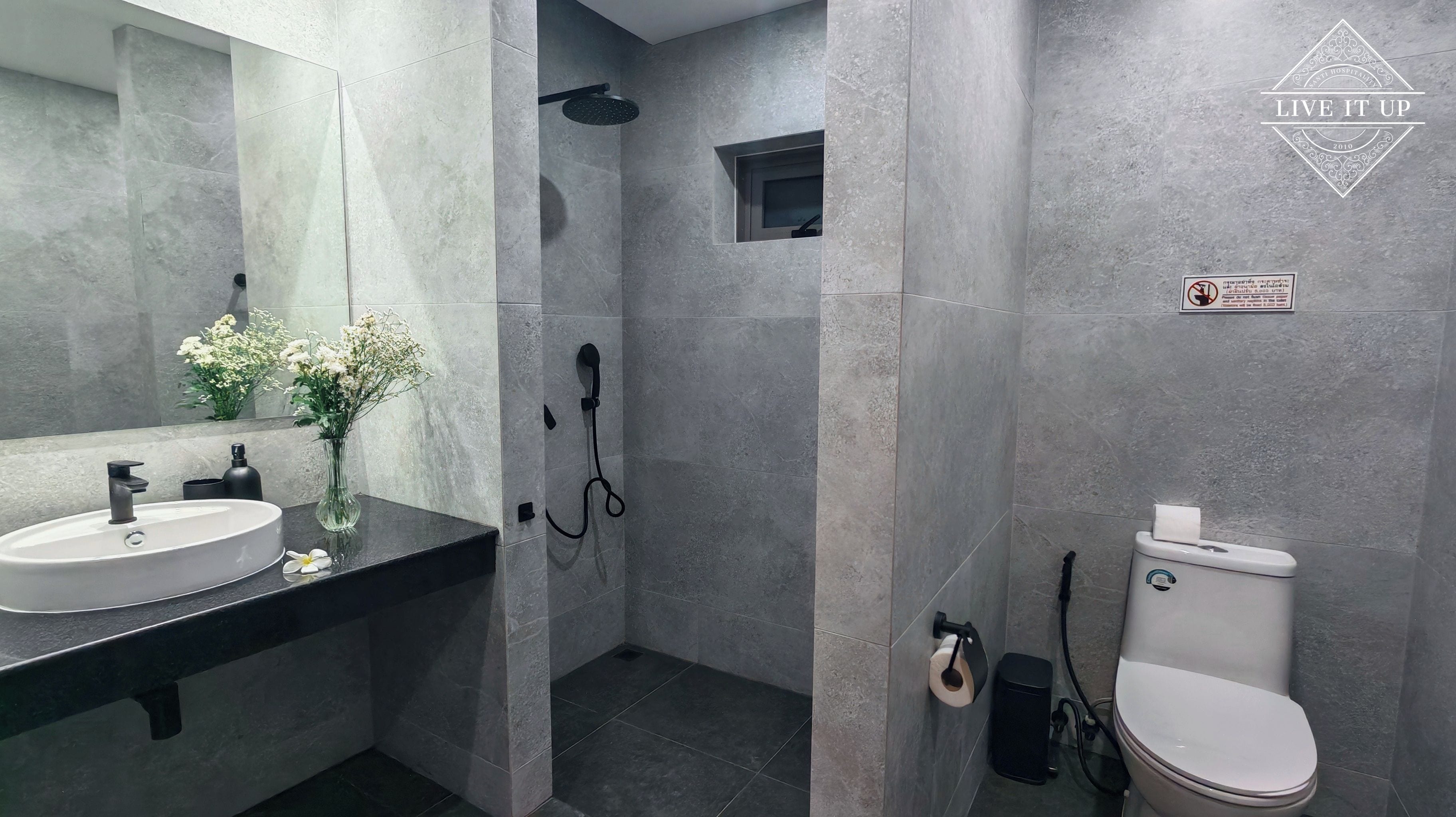A modern bathroom with a large mirror, a sink, a toilet, and a shower area.