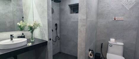 A modern bathroom with a large mirror, a sink, a toilet, and a shower area.