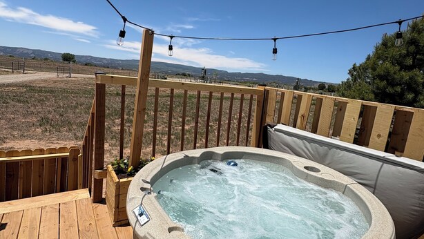 Un jacuzzi en una terraza de madera con una vista despejada del paisaje circundante.