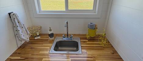 Cocina compacta con encimera de madera, un lavamanos y una ventana con vistas a un campo.