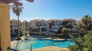 A resort with a swimming pool, multiple-story buildings, and palm trees. - Cassiopeia 3-Bedroom House on beach with pool (Chania)