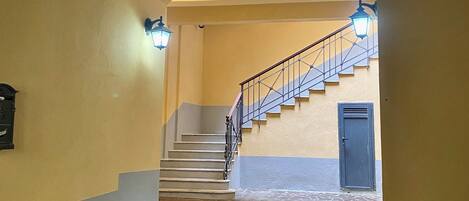 A staircase with a wooden handrail and a blue door at the bottom.