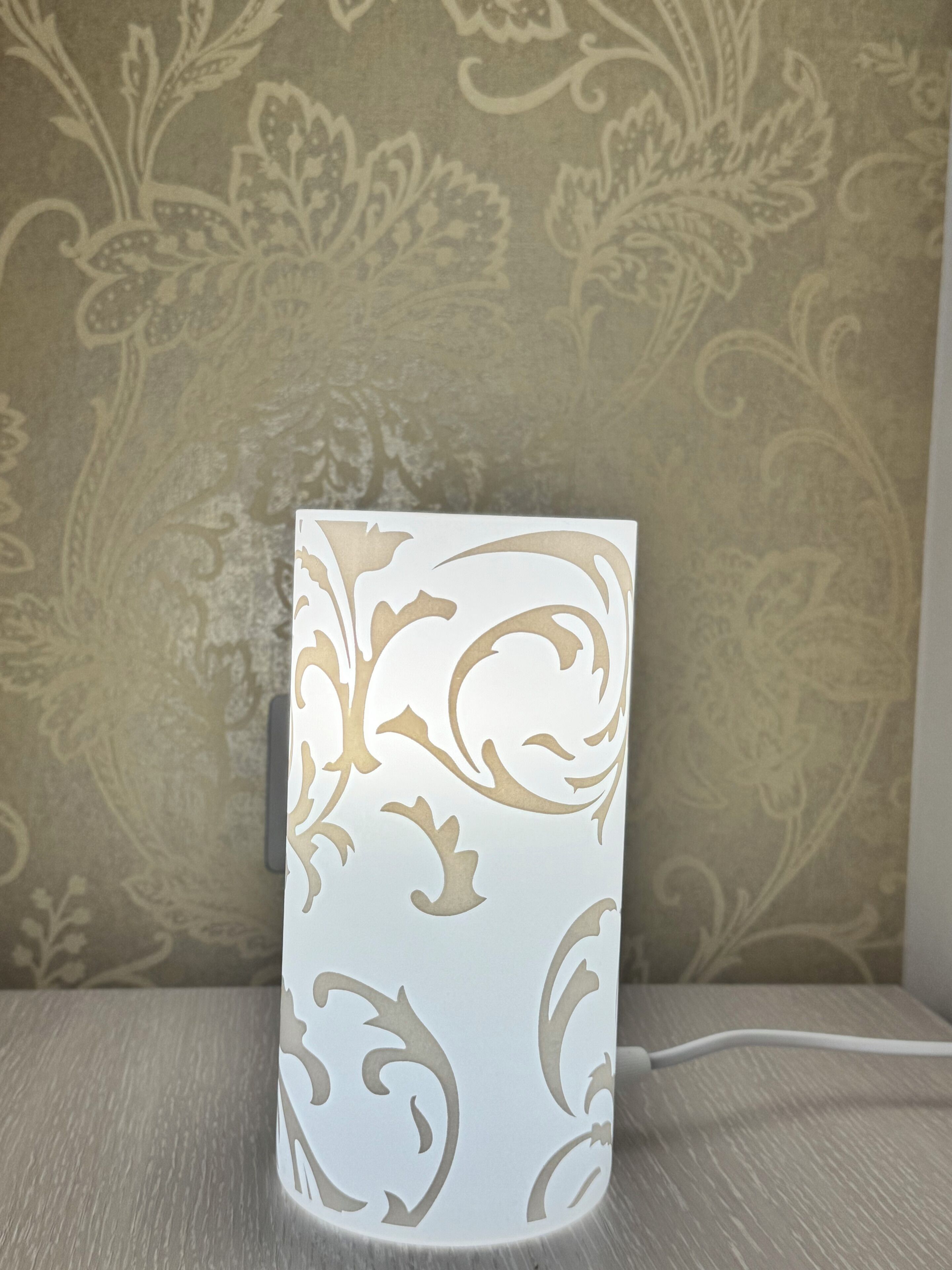 Una lámpara blanca con un diseño decorativo en una pared con textura.