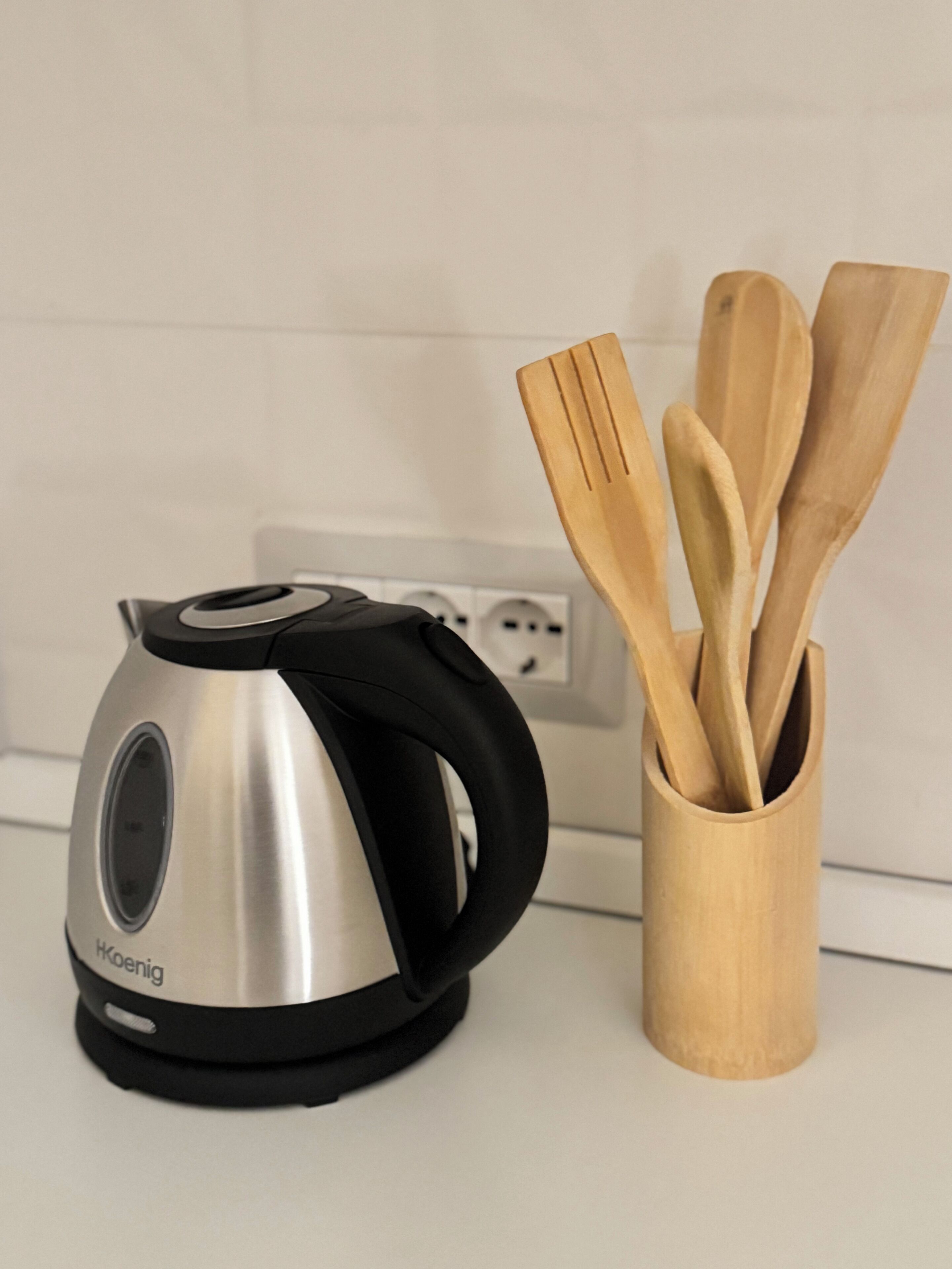 Une bouilloire et des ustensiles de cuisine en bois sur un plan de travail.