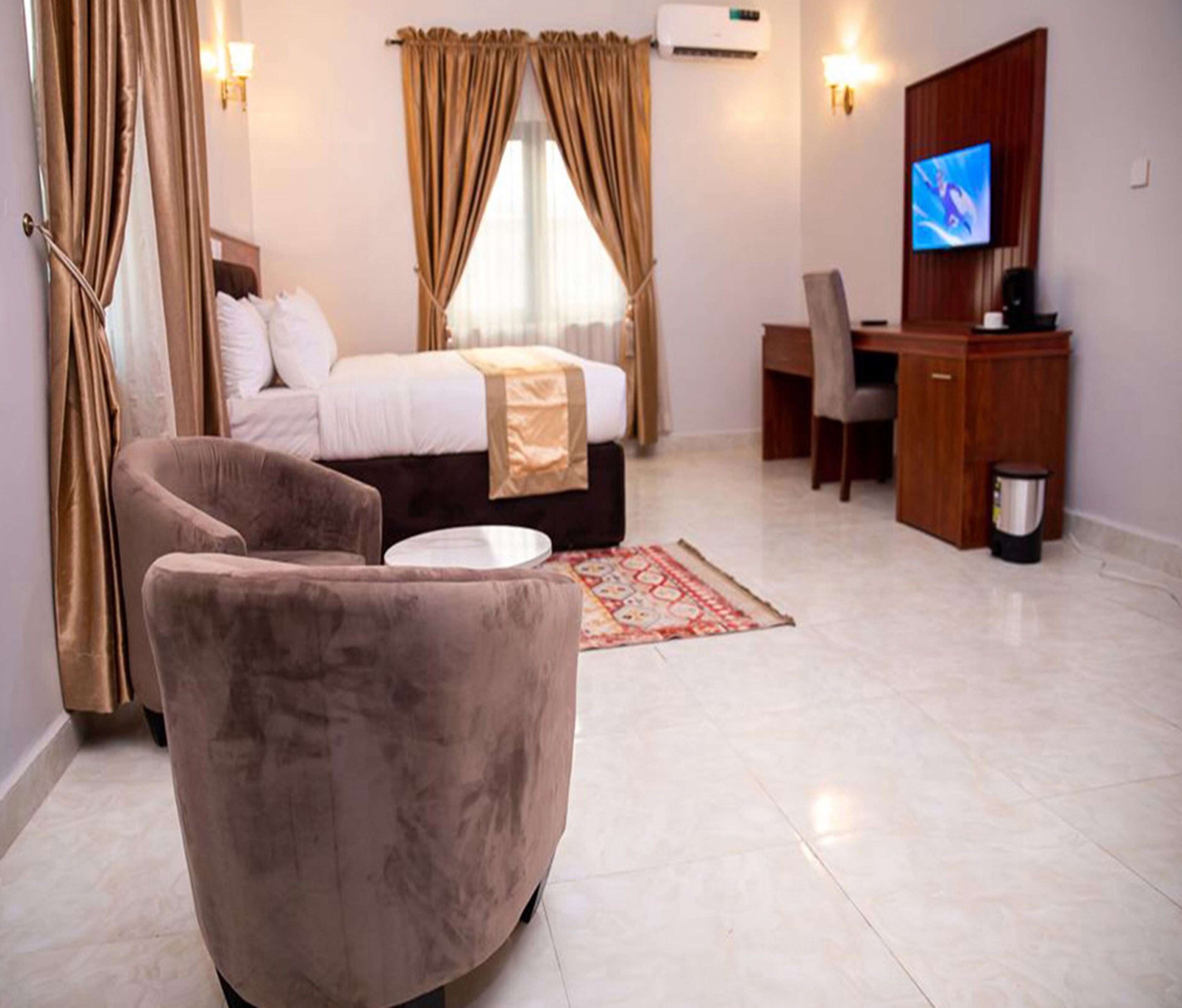A hotel room with a bed, a desk, a TV, and a chair.