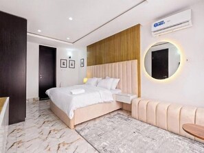 Une chambre moderne avec un grand lit, des tables de chevet, un miroir rond et un appareil de climatisation.