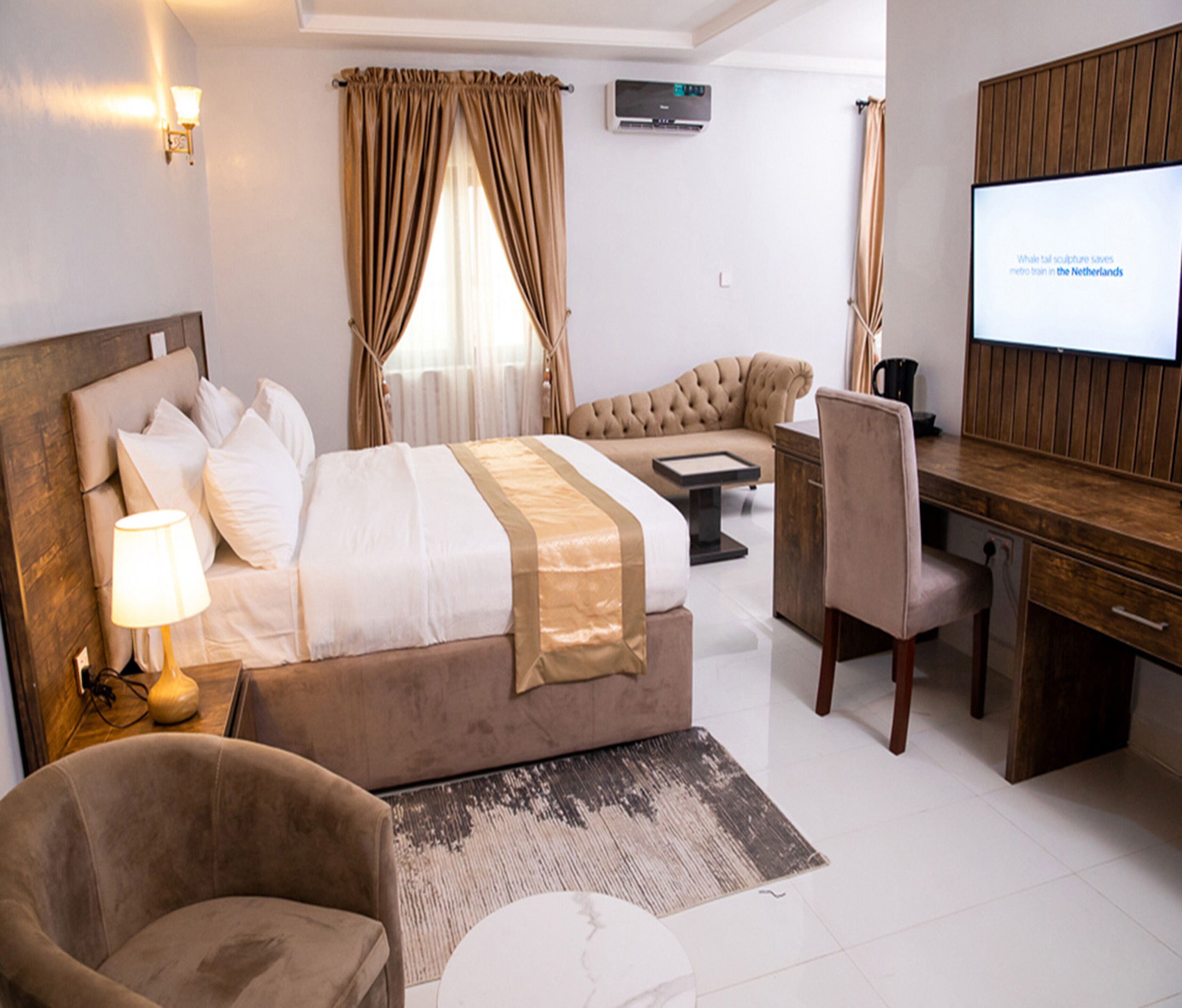 Een hotelkamer met een bed, een bureau, een stoel, een televisie en een bank.