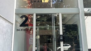 Un edificio moderno con entrada de vidrio, un número de teléfono visible y un cartel que dice "UNIT SMART LIVING".