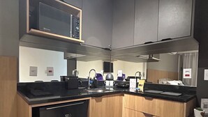 Una cocina compacta con microondas integrado, lavavajillas y armarios de madera.