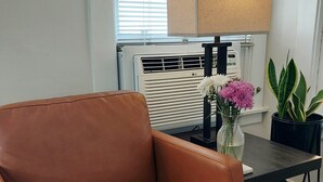A brown leather chair, a table with a vase of flowers, a potted plant, and a radiator with an LG logo. - STAY 5 MINUTES  AWAY (Oakland)
