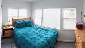 A bedroom with a bed, nightstand, dresser, and windows. - STAY 5 MINUTES  AWAY (Oakland)