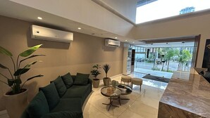 Eine moderne Lobby mit einer Couch, einem Couchtisch, Topfpflanzen und Blick ins Freie.
