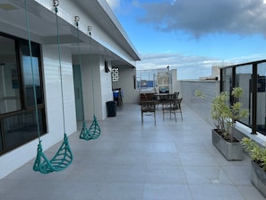A rooftop terrace with hanging chairs, a table, chairs, and potted plants. - Bela Hospedagem - 105 Compact Tambau (João Pessoa)